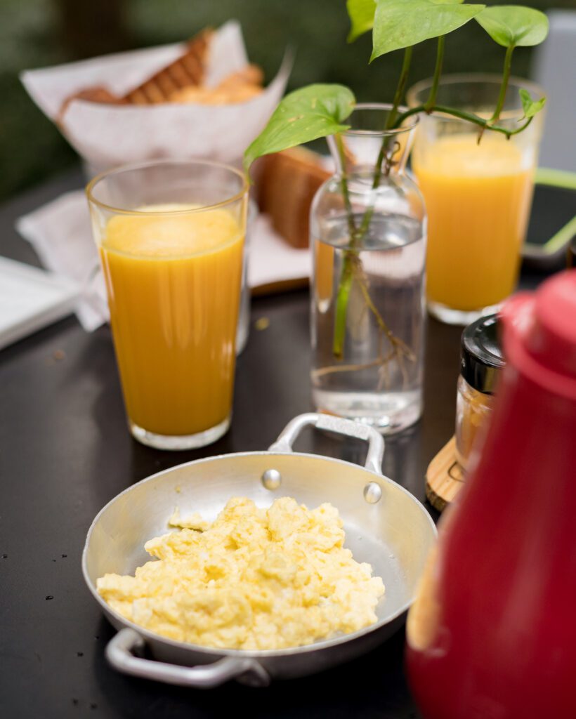 alguns itens do nosso café da manhã, nossa cesta de pães, suco de laranja e ovos mexidos